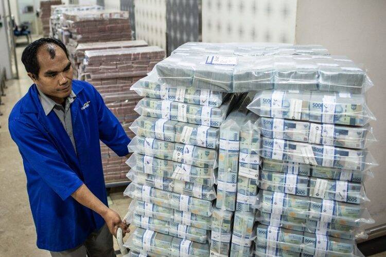 Petugas mendorong troli berisi tumpukan uang rupiah di Cash Center Bank Mandiri, Jakarta.